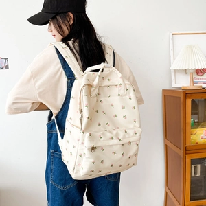 Floral print school backpack in beige worn by a model against a minimalist wall