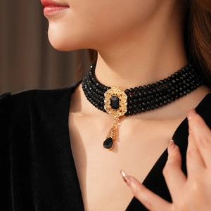 Detail view of vintage four-layer black beaded choker necklace with gold lace and pear drop