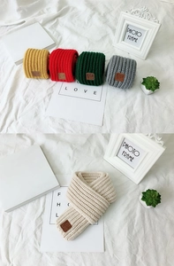 Detail showing five assorted colors of knitted children's scarves with leather labels