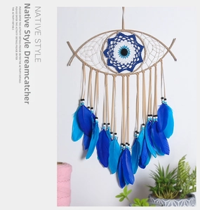 Detail of bohemian eye-shaped dream catcher with blue feathers on white wall