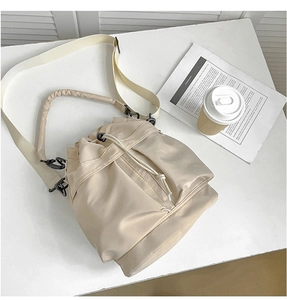 Top view of beige nylon bucket bag with adjustable straps and drawstring closure detail