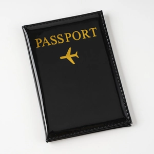 Funda de pasaporte en cuero PU negro brillante con icono de avión dorado y texto