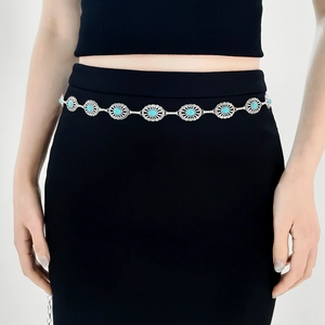 Detail of vintage carved metal chain belt with turquoise inlays on a black dress
