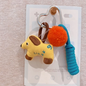 Detail of yellow fabric dog charm with orange pompom and blue rope on silver heart clasp