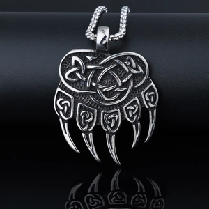 Macro view of silver bear paw pendant with Celtic knot patterns on a reflective surface