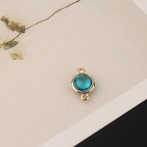 Detail of round gold-plated connector with light blue crystal for DIY jewelry making