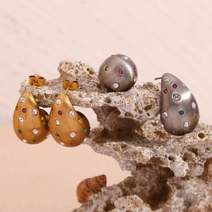 Détail des boucles d'oreilles goutte en or 18K brossé avec zircons colorés sur corail