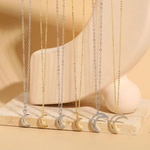 Collection of gold and silver moon pendants with zircon micro-paving on stone display