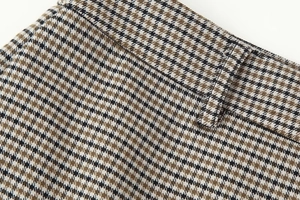 Detailed close-up of brown houndstooth fabric showing waistband and belt loops