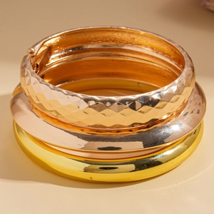 Detail of stacked gold and rose gold metal bangles with textured and polished finishes