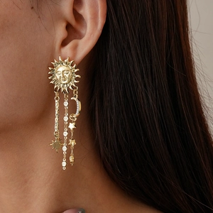 Close-up of golden sun and moon tassel earrings with sparkling rhinestones on model