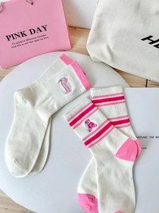 Detail of pink striped crew socks with cute bear and Bunny embroidery on a white plate