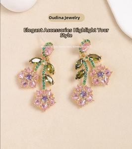 Macro detail of colorful floral drop earrings with pink zircons and green crystal accents