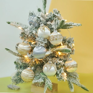 Close-up of 6cm glitter Christmas ornaments with stripes hanging on a flocked tree
