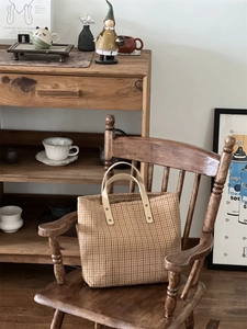 Detailed view of vintage plaid tote bag with leather handles on a retro wooden chair