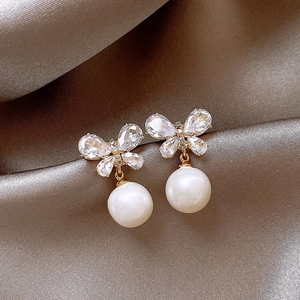 Macro view of gold bow earrings featuring sparkling zircons and a white pearl drop