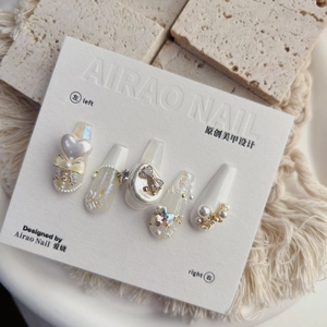 Macro view of 5D embossed nail stickers featuring pearls and golden bows on white base