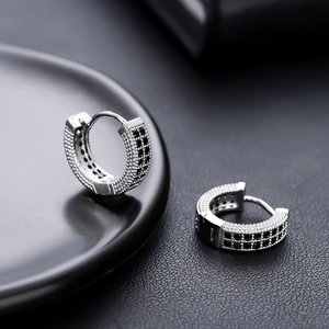 Vue macro de boucles d'oreilles huggie argentées avec pavé de zircons noirs et blancs
