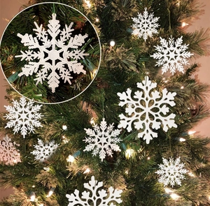 Detailed close-up of white glitter snowflakes hanging on a festive Christmas tree