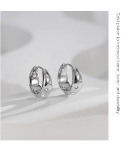 Detail of silver C-shaped hoop earrings with clear crystals on a textured white stand
