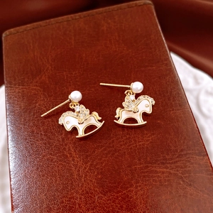 Détail de boucles d'oreilles cheval à bascule plaquées or 14 carats et émail blanc