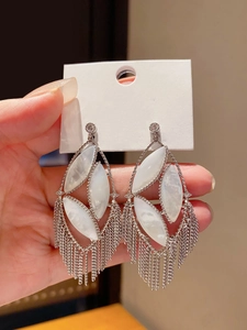 Detailed view of silver oval earrings featuring shell inlays and long layered metal tassels