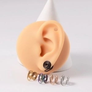 Macro shot of spiral non-piercing ear clips in five metallic colors on an ear model