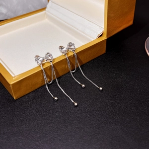 Detailed view of silver bow tassel earrings with sparkling crystals on black leather