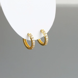 Close-up of small gold S925 sterling silver hoop earrings set with sparkling zircon stones