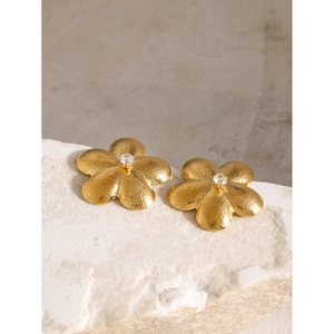 Detail of 18k gold plated flower stud earrings with brushed texture and zircon center