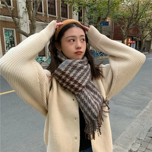 Classic houndstooth scarf with tassels in brown and blue, worn by a model in a street setting