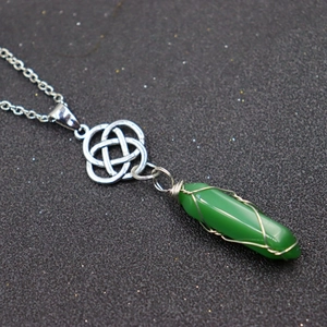 Macro detail of a green hexagonal stone pendant with silver wire wrap and Celtic knot