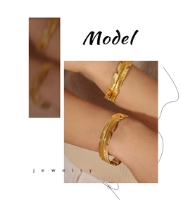 Detailed view of a gold feather-shaped open cuff bracelet worn on a woman's wrist