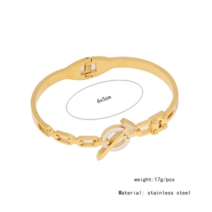Macro detail of gold stainless steel cross bangle showing dimensions 6x5cm and 17g weight
