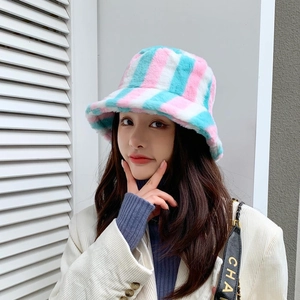 Close-up of a rainbow striped plush bucket hat in pink, white, and blue on a model
