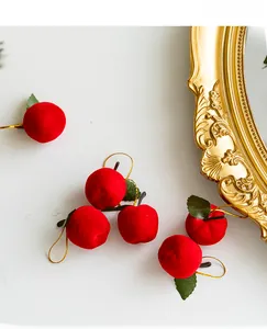 Close-up of red flocked Christmas apple ornaments with green leaves and gold strings