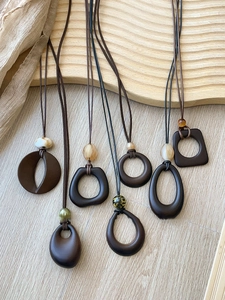 Close-up of bohemian geometric resin pendants with amber beads on minimalist cord necklaces