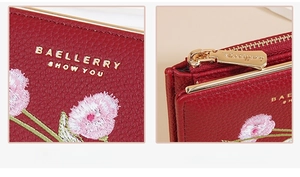 Close-up of floral embroidery on lychee leather and gold hardware zipper brand details