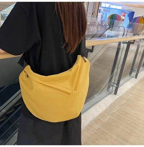 Detail of yellow nylon crescent crossbody bag with black adjustable strap and zipper