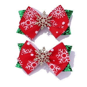Detailed view of handmade Christmas hair bows with green glitter and red snowflake ribbons