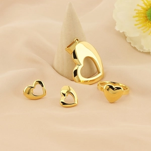 Elegant gold heart jewelry set with necklace earrings and ring on a soft fabric base