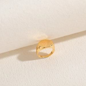 Detailed macro view of an oval signet ring in 14K gold plated finish on white backdrop
