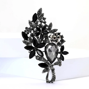 Macro view of vintage style alloy brooch with black and gray crystals on white pedestal