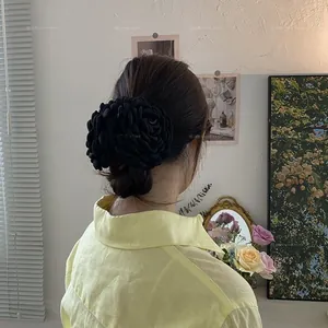 Vista dettagliata di una grande clip per capelli a fiore nero in tessuto 3D su uno chignon