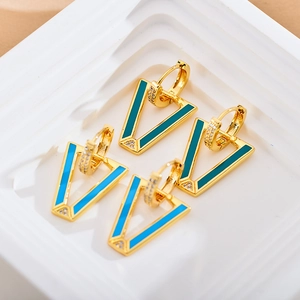 Macro detail of V-shaped gold earrings with blue green enamel and zircon stones
