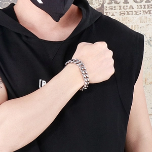 Men's silver Cuban link stainless steel bracelet shown on wrist in street style setting