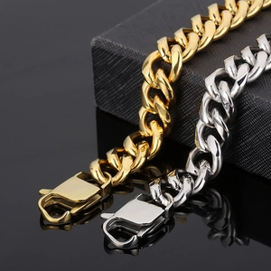 Detailed view of gold and silver cuban link chains with heavy lobster clasps on black surface