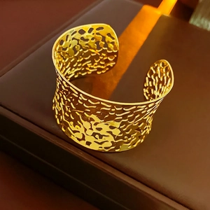 Golden irregular hollow open cuff bracelet displayed on a dark luxury jewelry box