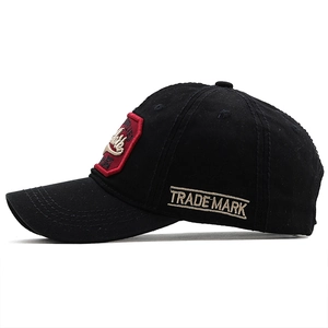 Side view of black washed cotton baseball cap with gold Trade Mark embroidery detail