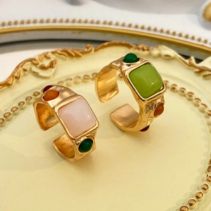 Conjunto de anillos dorados vintage con gemas coloridas en una bandeja decorativa retro